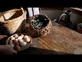 Indigo stalk nest basket with ceramic eggs in a bed of dried indigo leaves