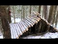 Construction of a comfortable log shelter on the mountainside. Bushcraft in a cold winter forest