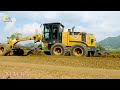 Amazing road construction in a rural area. The large yellow motor grader is working on a dirt road