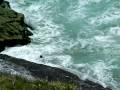 People jump off coastal rocks into heavy surf at Yamba, NSW