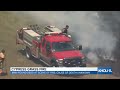 Firefighters use brooms to fight grass fire in Cypress, Texas