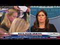 Between reporters, Sarah Sanders at White House press briefing (FNN)